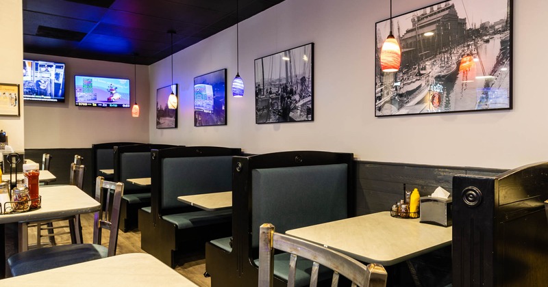 Interior, dining booths by a wall with vintage photo prints and TVs