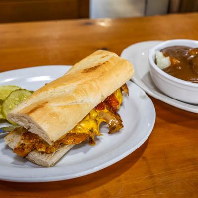 BBQ chicken sandwich served alongsdie mashed potatoes topped with gravy.