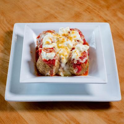 Portion of Meatballs topped with marinara sauce and cheese.