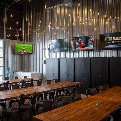 Dining area, long tables with chairs and TVs on walls.