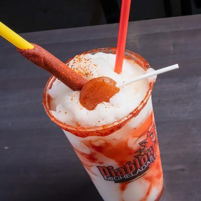 Spicy lime margarita topped with a tamarind candy stick and a lollipop.