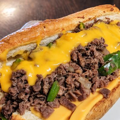 A cheesesteak roll filled with chopped beef, green peppers and melted yellow cheese..