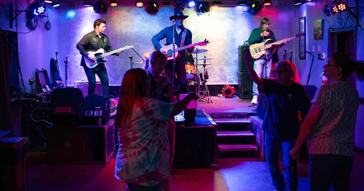 Interior, live music performance featuring a band playing on stage and patrons dancing