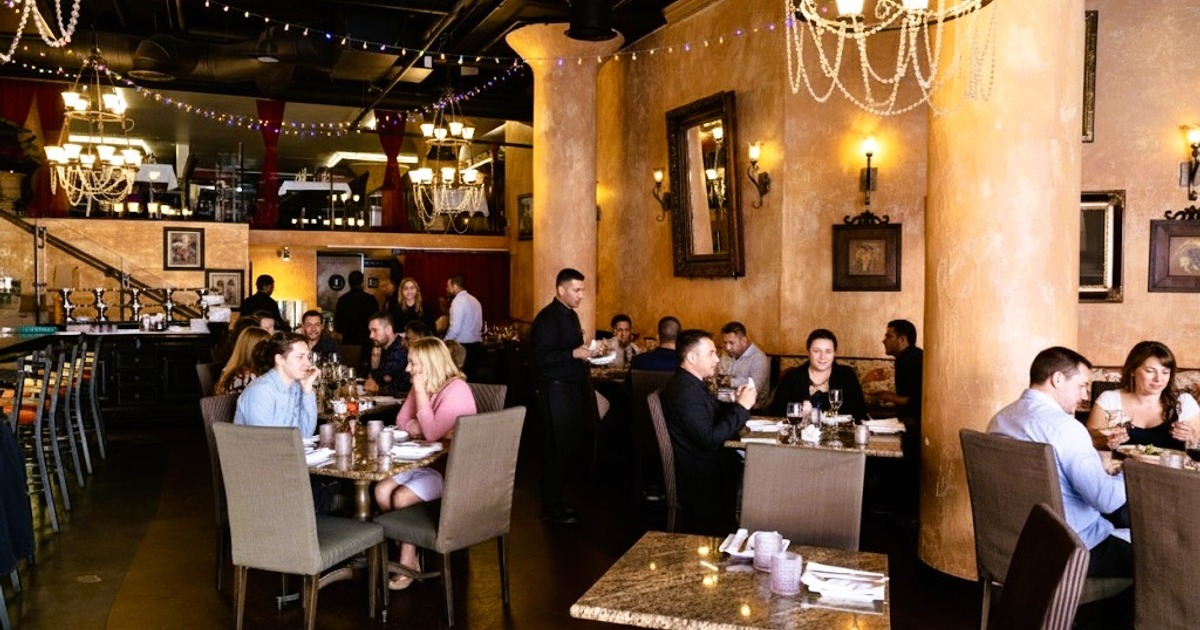 Guests dining during a private event in Il Sogno Italiano’s main dining room beneath chandeliers and string lights.