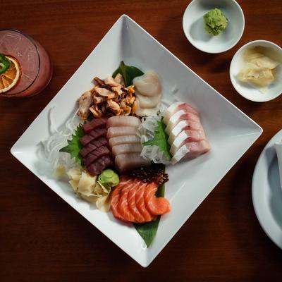Sashimi plate served with condiments and a cocktail, top view.