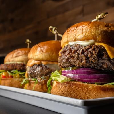 Three cheeseburgers topped with lettuce onion and pickles.