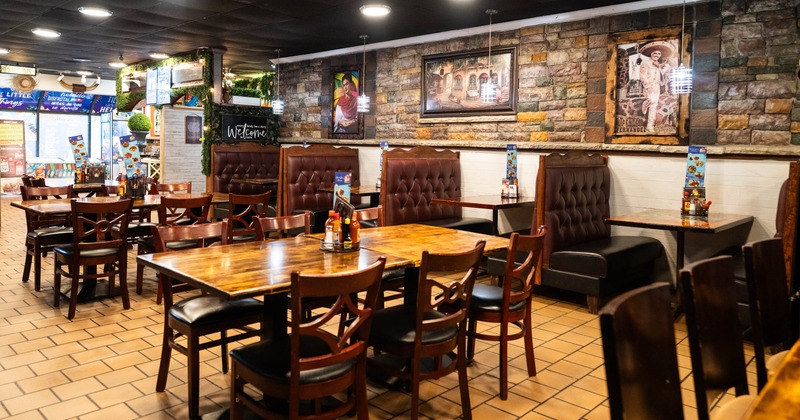 Interior of a warm, rustic restaurant with wooden tables and tufted booths