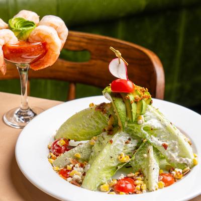 Wedge salad with blue cheese dressing, cherry tomatoes, avocado and crumbled bacon.
