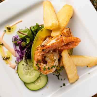 A gourmet dish with shrimp, fries, avocado, and salad.