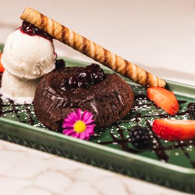 Chocolate lava cake with vanilla ice cream, a wafer stick, blackberries, strawberries.