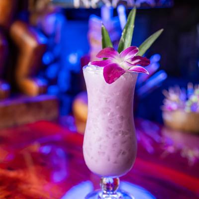Ube colada cocktail garnished with orchid flower.