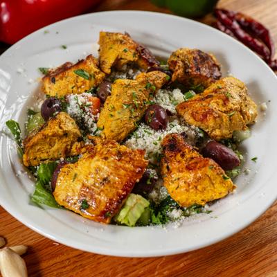 Grilled chicken shish kebab served over fresh salad, feta cheese, and olives.