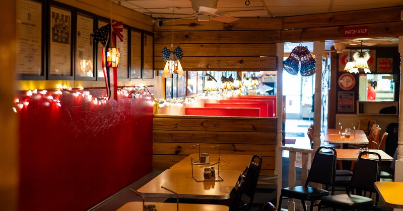 Interior of a cozy restaurant with red booths and wooden tables