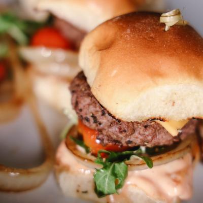 Cheeseburger sliders with tomato, onion and arugula, close-up.