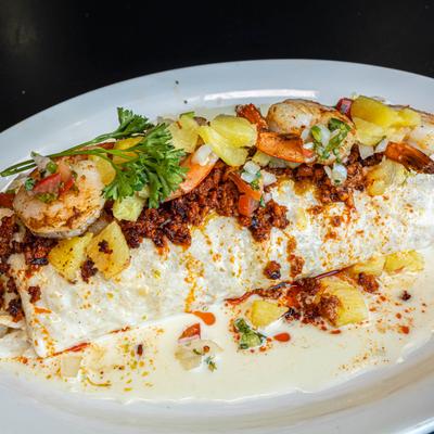 Burrito topped with chorizo, shrimp, and pineapple salsa.
