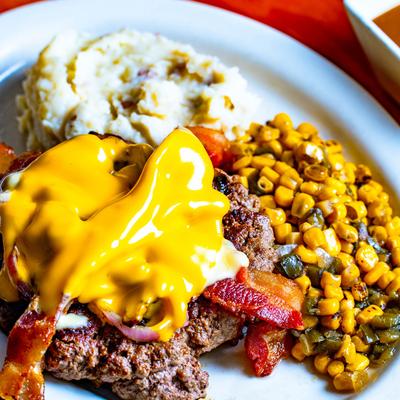 Hamburger steak, served with poblano corn and mashed potatoes, close up.