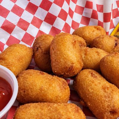 Golden mini corn dogs in a red-and-white checked basket with dipping sauce..