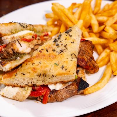 Chicken focaccia sandwich with a side of fries, close up.