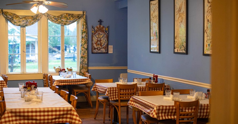 Interior, tables and chairs lined up, framed pictures on the wall