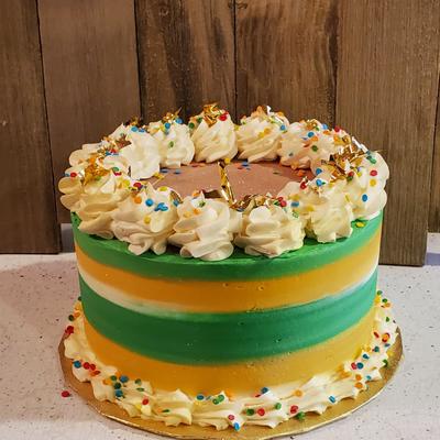 Cake with green and orange stripes, topped with whipped cream swirls and sprinkles.