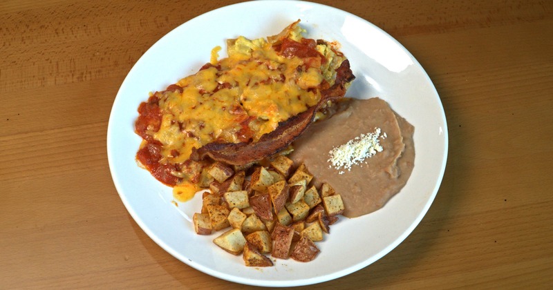 Tortilla chips smothered in cheese and red sauce, served with potatoes and beans
