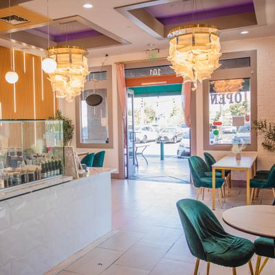 Bright modern cafe interior featuring green chairs, crystal chandeliers, and white counte.