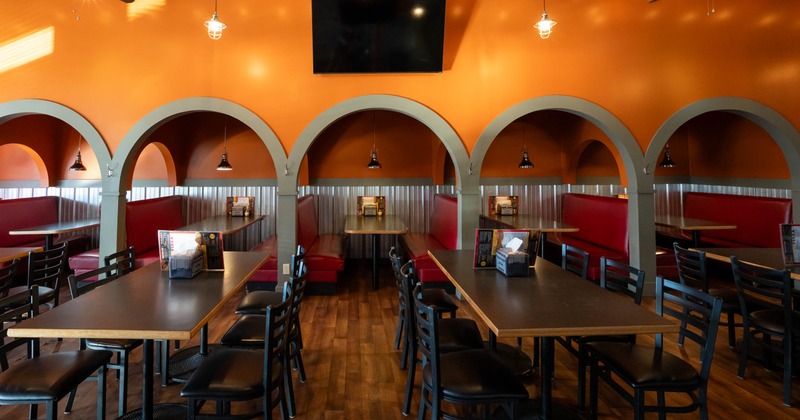 Interior, seating area with tables, chairs and booths in the back