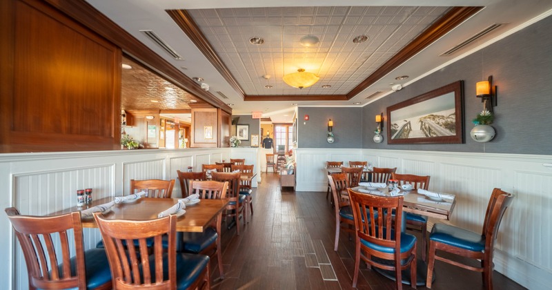 Interior, dining area, tables for four and two, ready for guests, padded wooden chairs