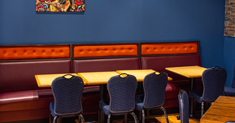 Dining area with booth seating, blue chairs, wooden tables, and colorful wall art
