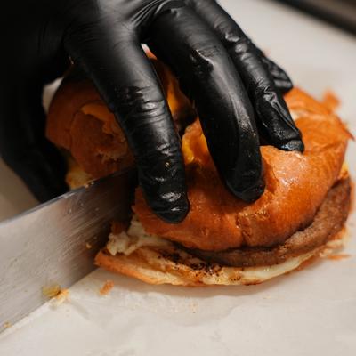 Chef cutting a croissant sandwich in half.