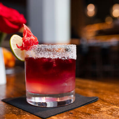 Red cocktail with a lime and sugared rim