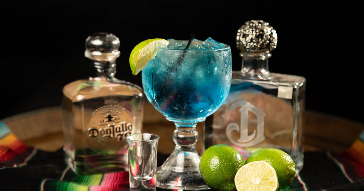 Blue Margarita, tequila bottles and lime on a table with  traditional blanket