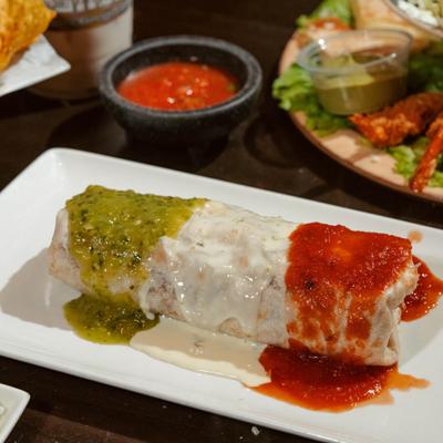 Burrito Mexicano topped with cheese sauce, tomatillo sauce and red sauce.