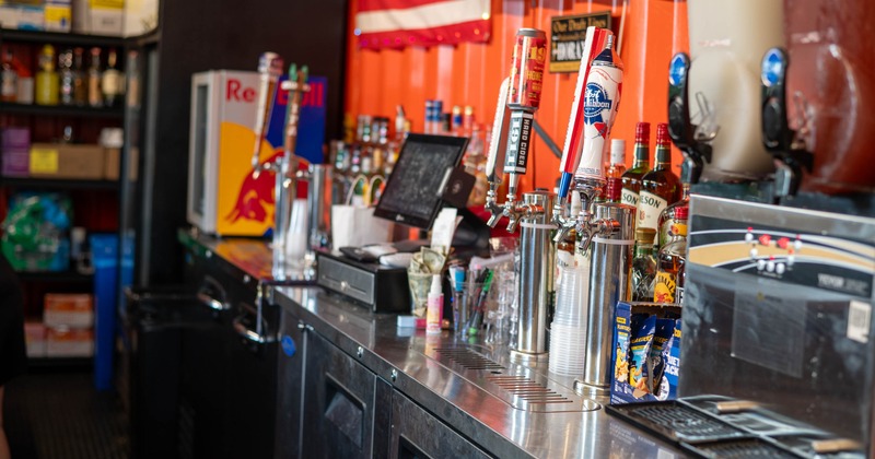 Stainless steel bar counter featuring draft beer taps, bottles, and equipment