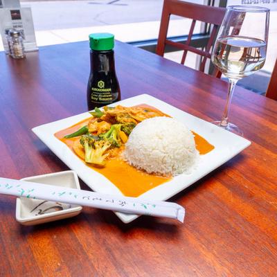 Stir-fried chicken and broccoli in a rich sauce, served with rice and white wine.