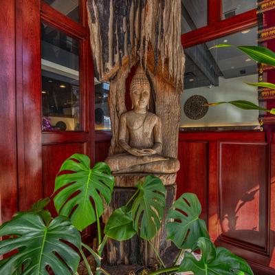 A wooden Buddha statue surrounded by green plants.