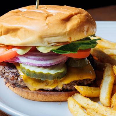Cheeseburger topped with dill pickles, red onions, tomato, and lettuce, served alongside fries.