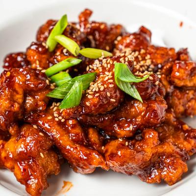 Korean fried chicken garnished with sesame seeds and green onions.