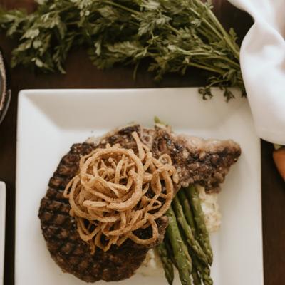 Grilled steak topped with crispy onions, served with asparagus.