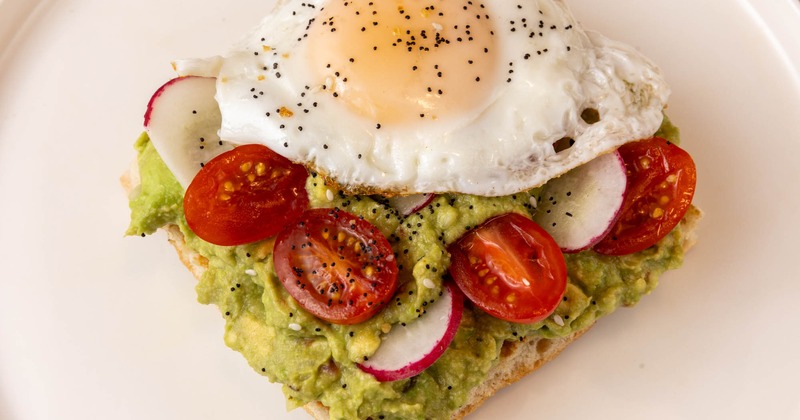 Avocado toast, with cherry tomatoes, radish, and a fried egg