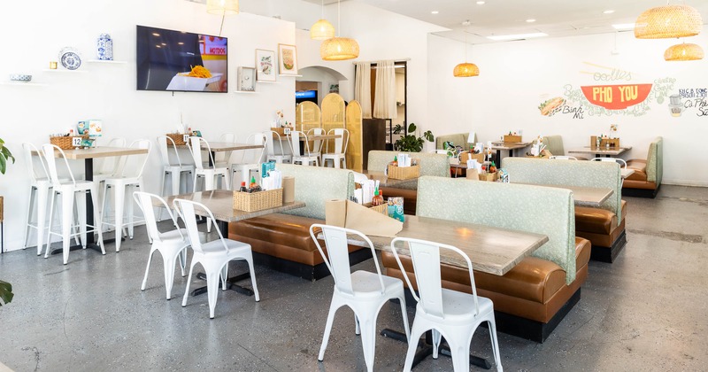 Interior, modern, well-lit dining area with booths, tables, white chairs and pendant lights