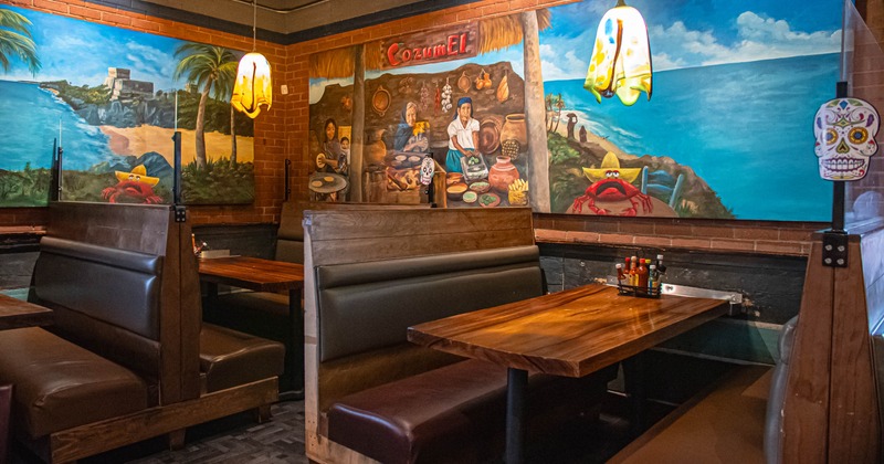 Interior of a restaurant with wooden booths and colorful murals on the walls