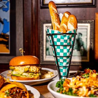Burger served alongside pretzel sticks and other menu items.