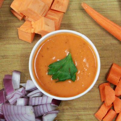 Soup of the day, soup bowl  served on a table with cut red onion and carrots, top view