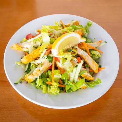 A salad with marinated chicken, onions, and cucumber.