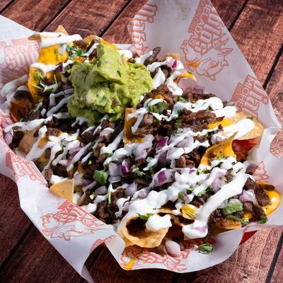 Carne asada nachos topped with guacamole, sour cream, cilantro, and onions.