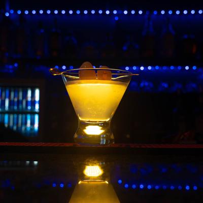 Lychee Martini on a bar with blue lights in background.