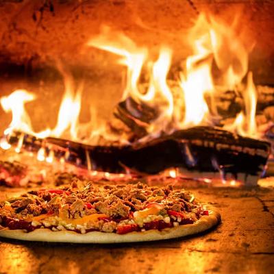A pizza being cooked in a wood-fired brick oven.