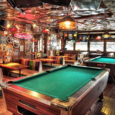 Room with pool tables, booths with colorful seating, colorful retro decor