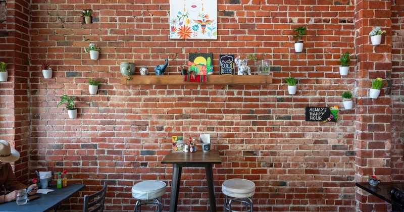 Bar table for 2 and chairs, decorated brick wall behind